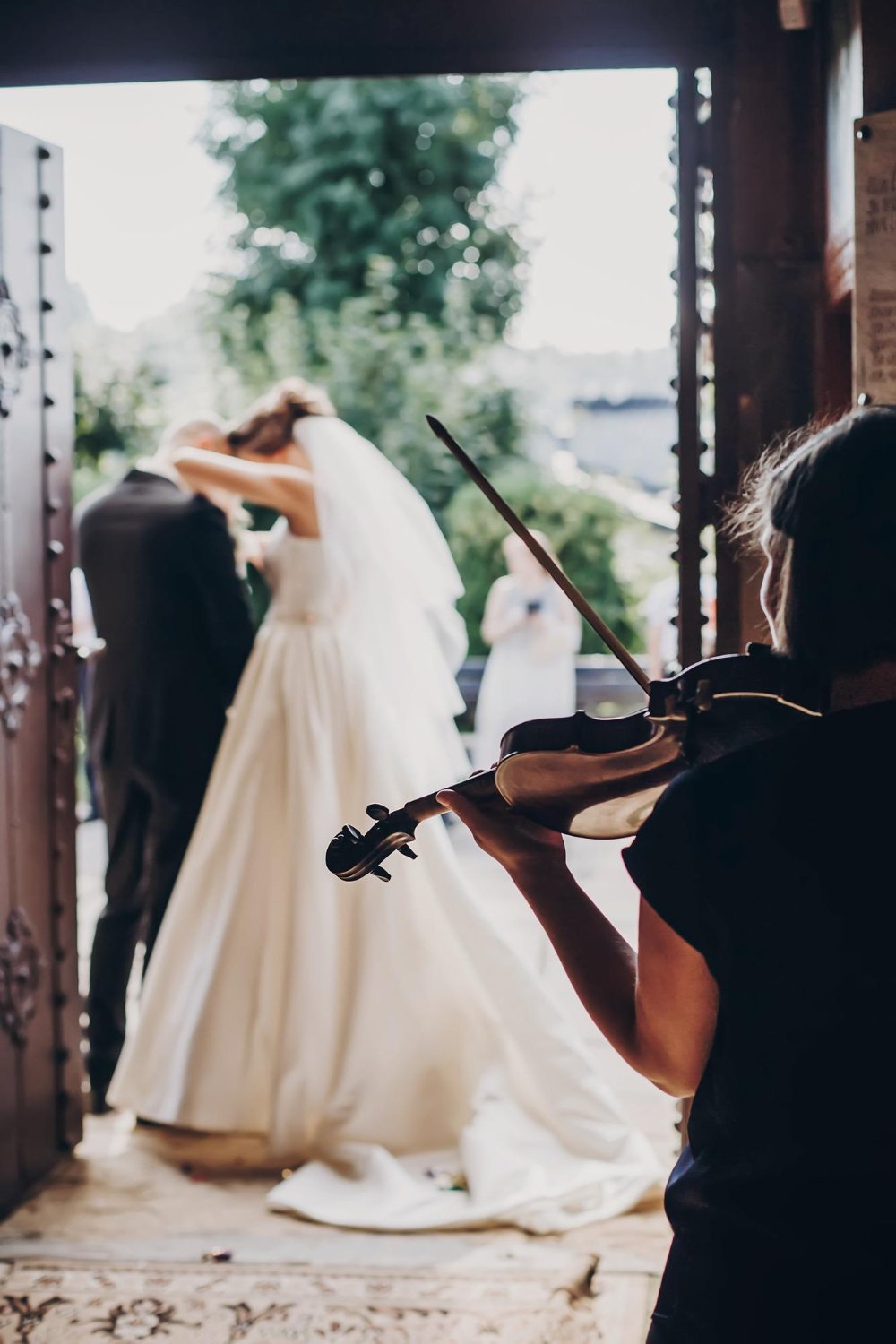 musician playing on violin while beautiful bride and groom
